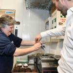Jenifer Burton, with a bit of help from franchise owner Greg McAuley, iced one of the Special Olympics donuts when she and other athletes visited the restaurant. (Heather Colpitts/Langley Advance Times)